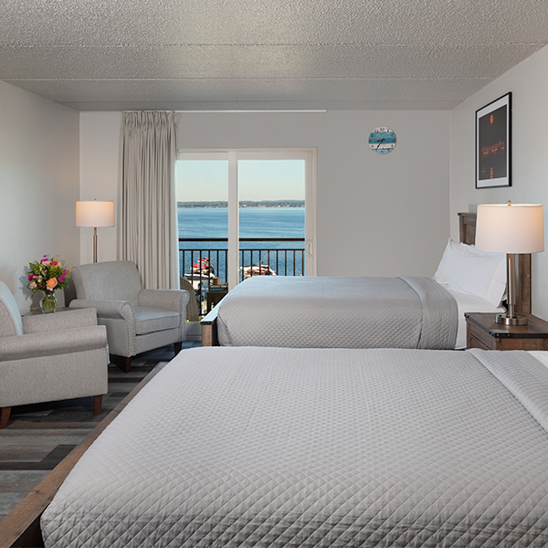 a room with two beds and a balcony overlooking the water