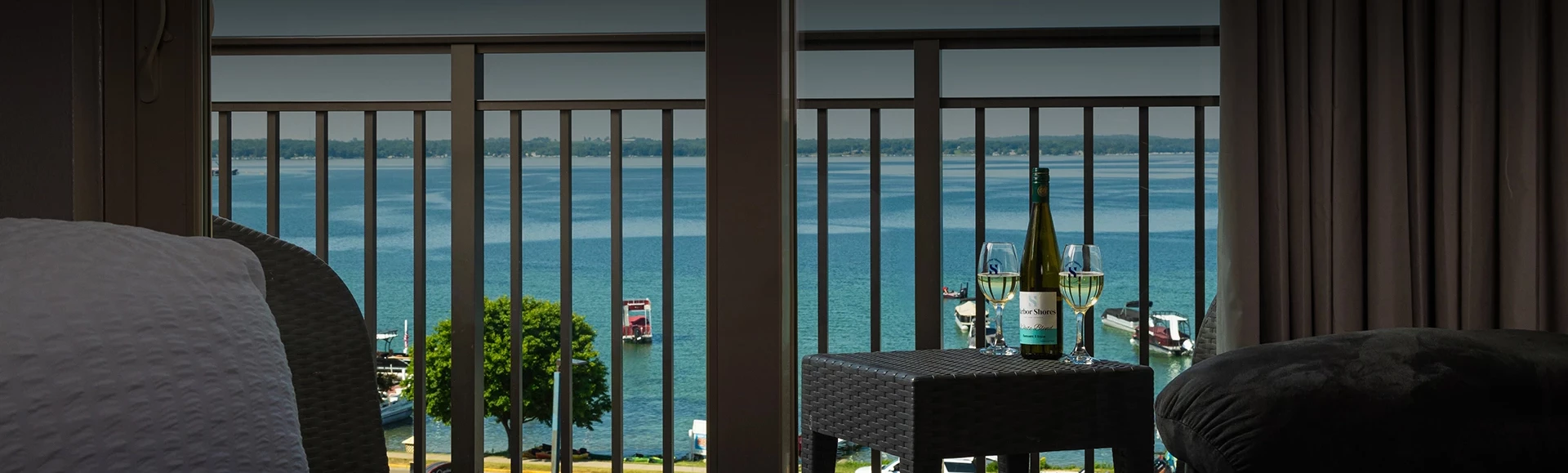 a table and chair with a glass of wine on a balcony overlooking a body of water