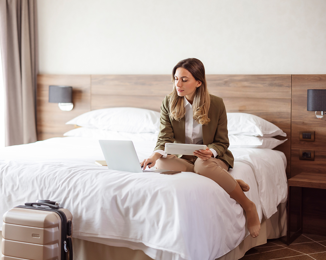 a woman sitting on a bed with a laptop