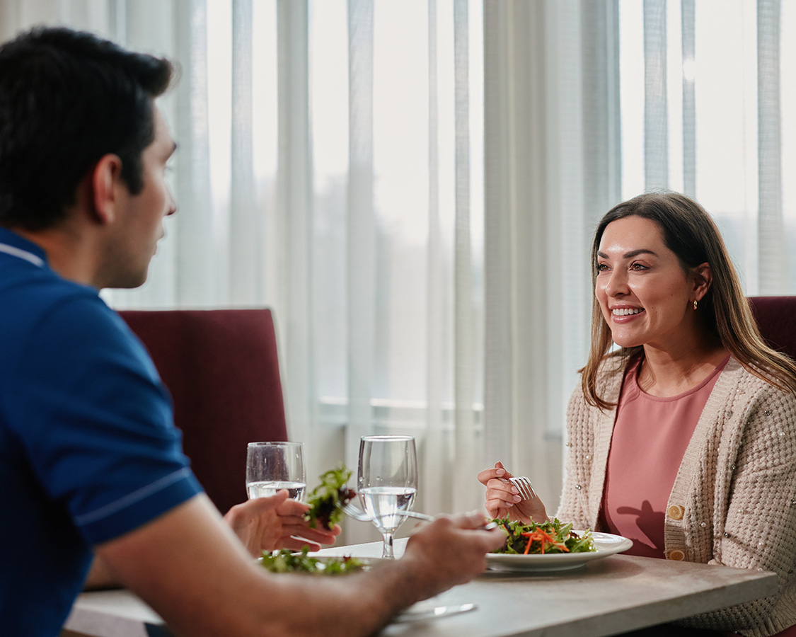 a man and woman sitting at a table with plates of food