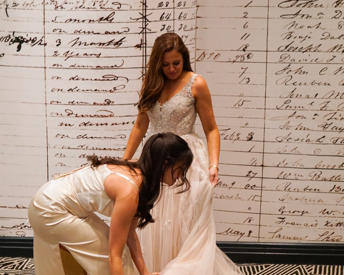 a woman in a dress kneeling on another woman in a dress