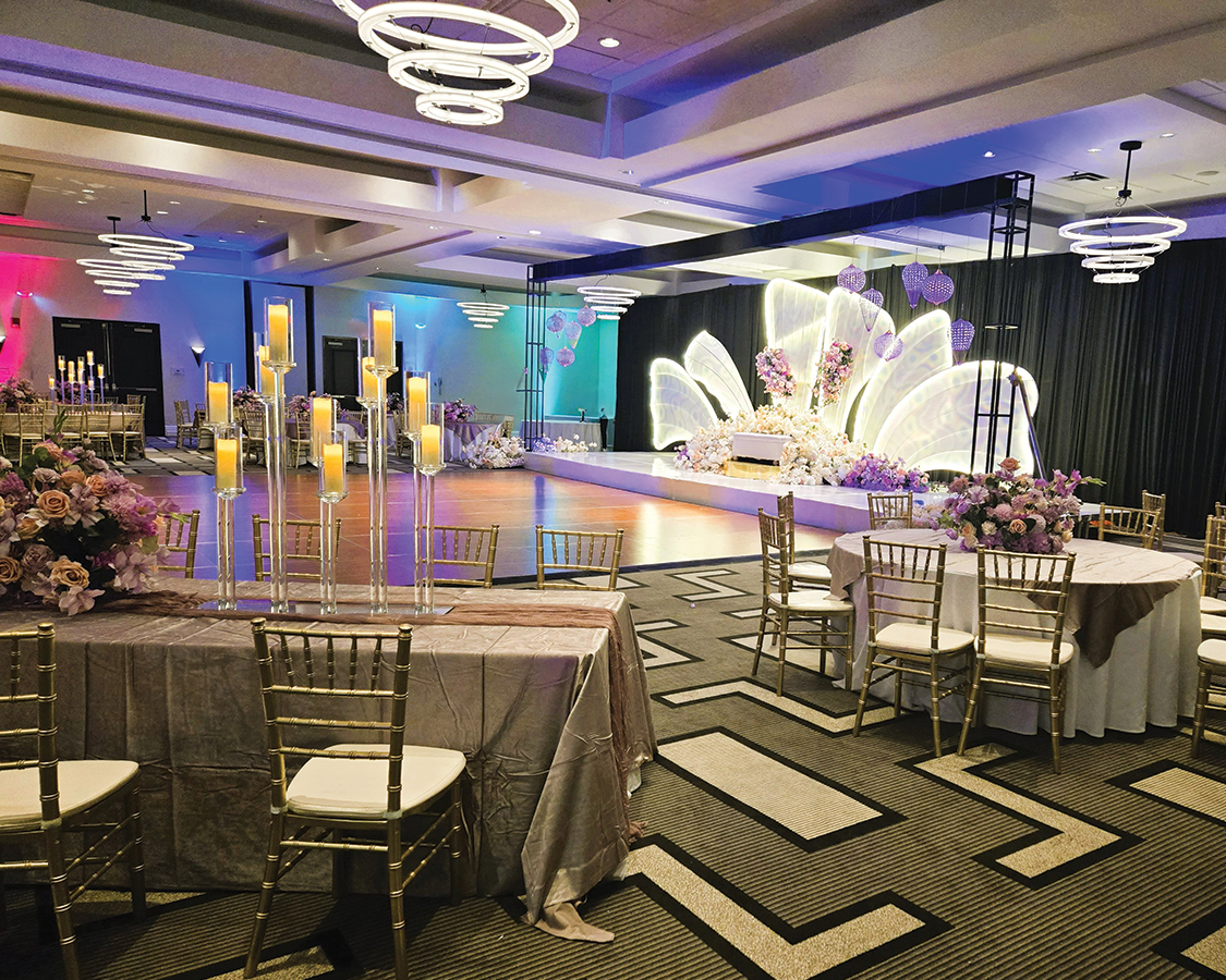 a room with tables and chairs and a stage with candles
