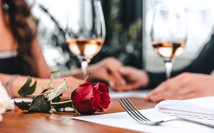 a rose and wine glasses on a table