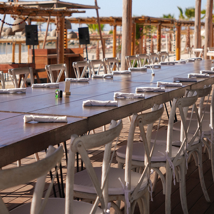 a long table with white chairs and napkins