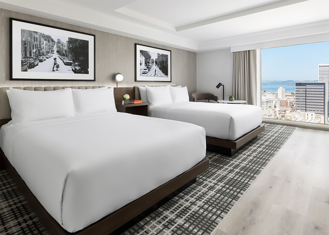 a room with two beds and a window overlooking a city