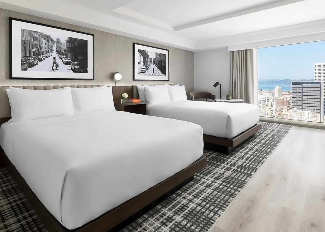 a room with two beds and a window overlooking a city