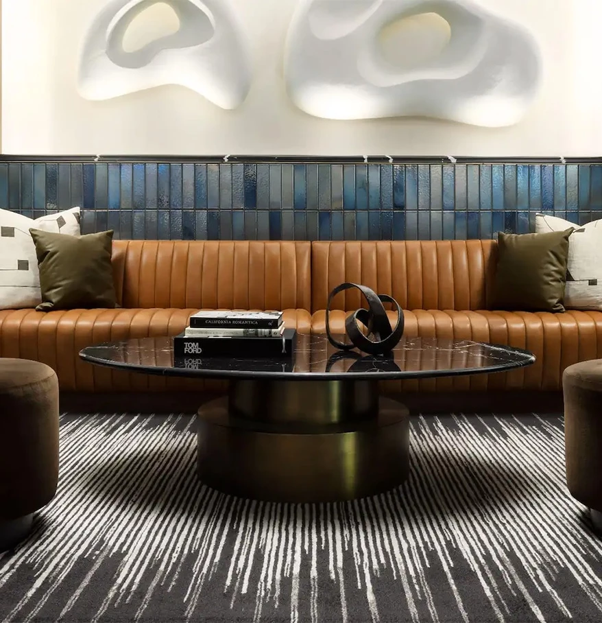 a brown couch with a round coffee table in front of a wall