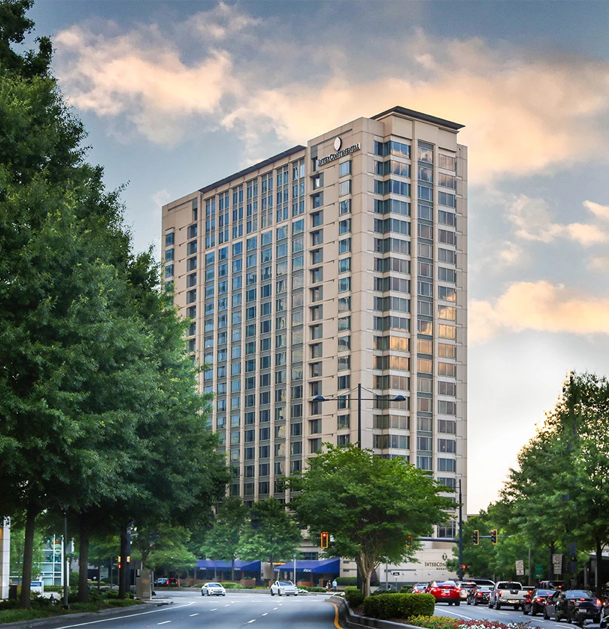 a tall building with trees and cars on the street
