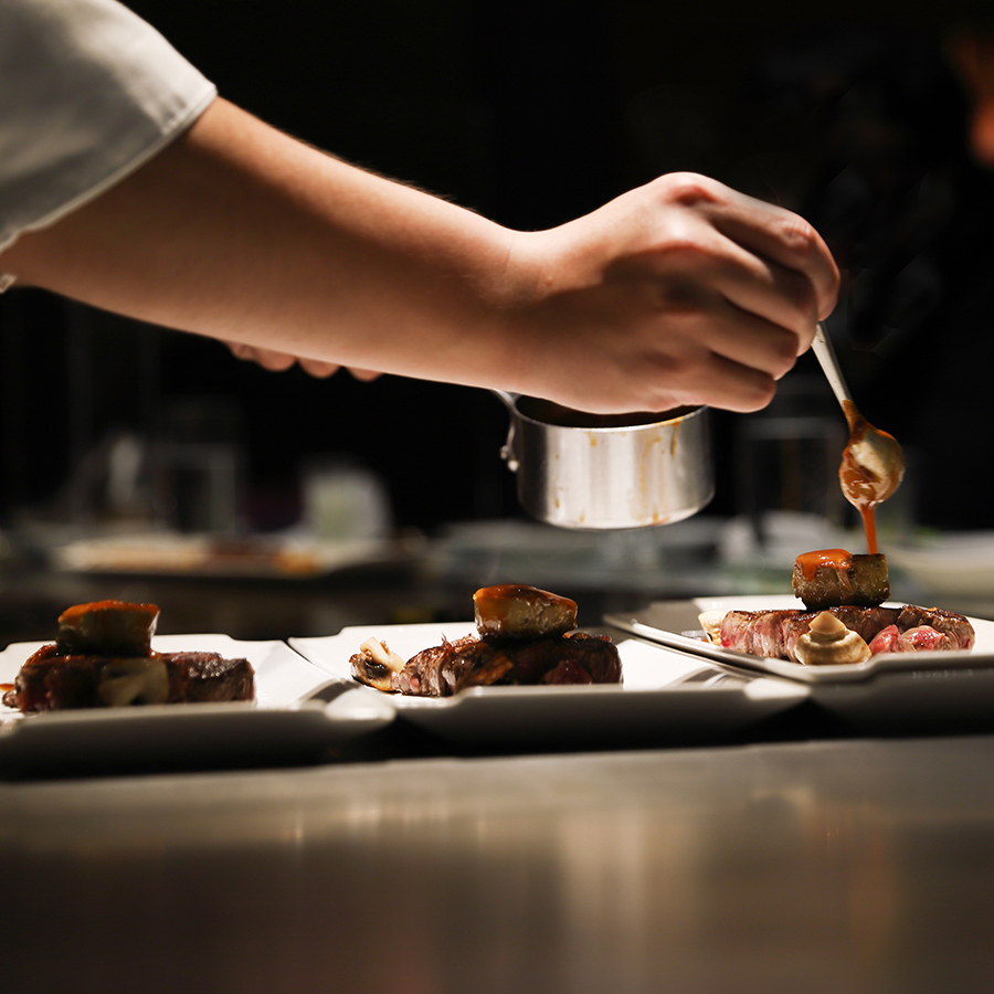 a person pouring sauce on food