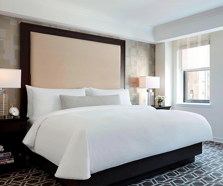 a bed with a large headboard and lamps in a room