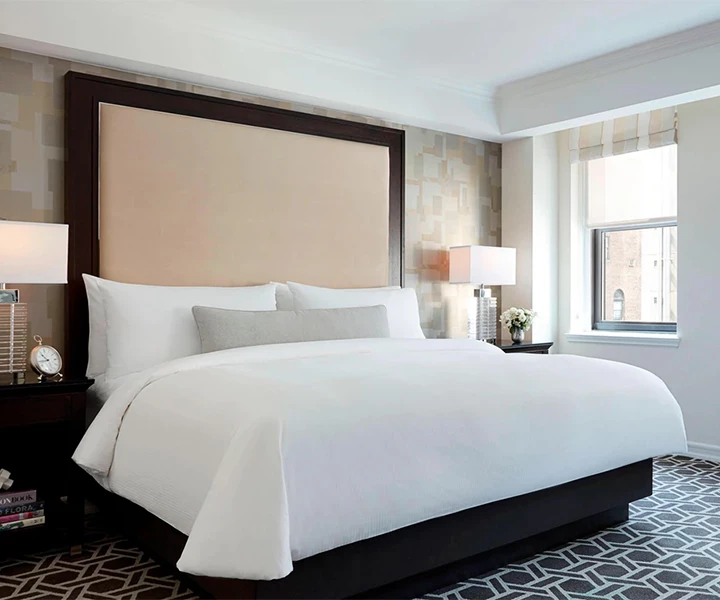 a bed with a large headboard and lamps in a room