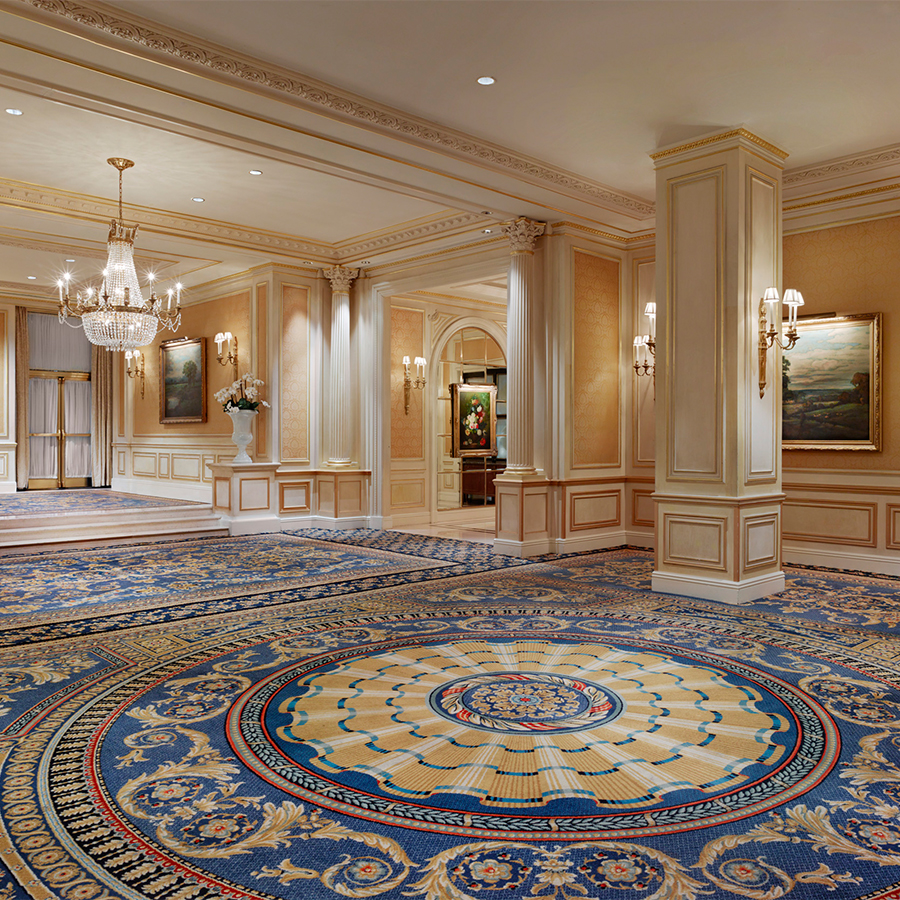 a large luxury room with a blue carpet and chandeliers