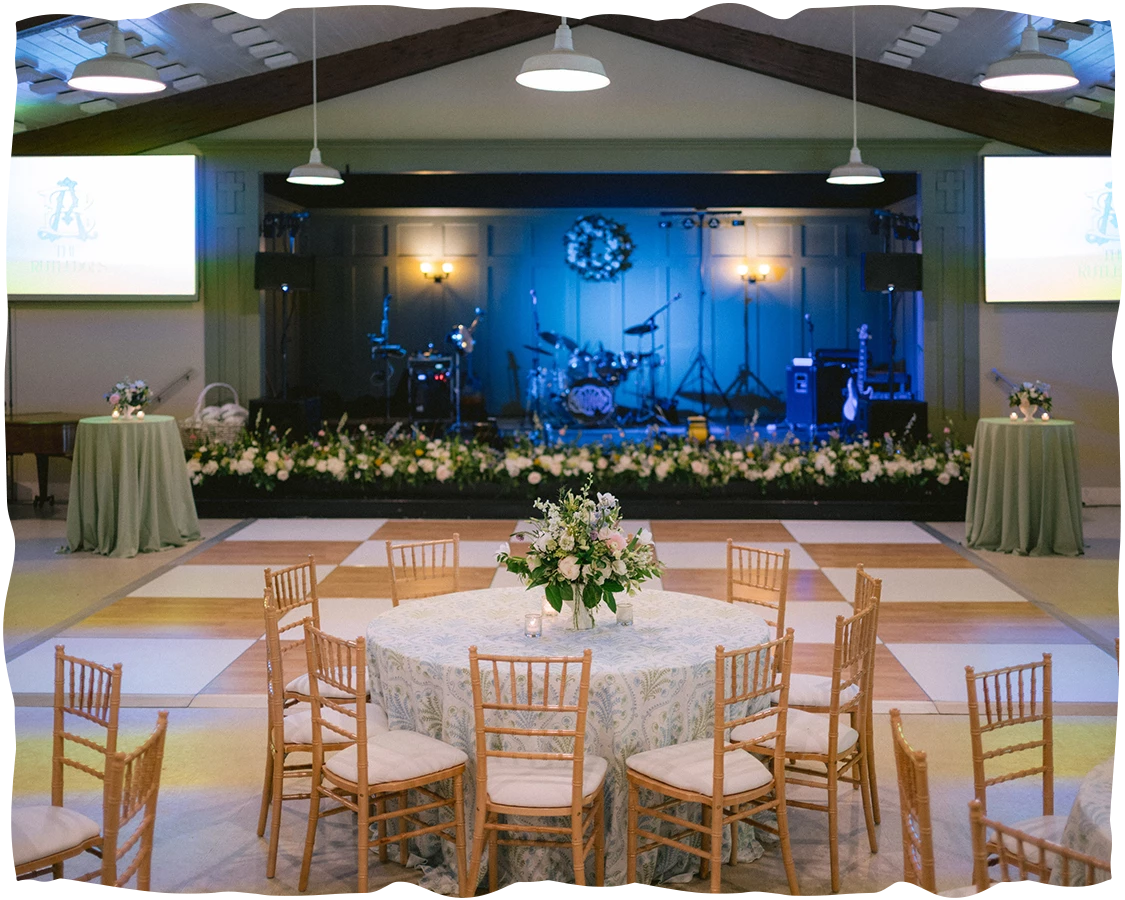 a room with a table and chairs and a stage with a band on the stage