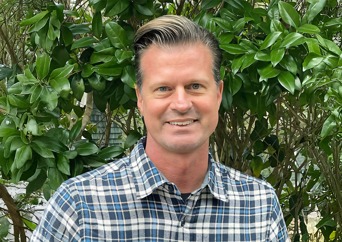 a man smiling in front of a tree