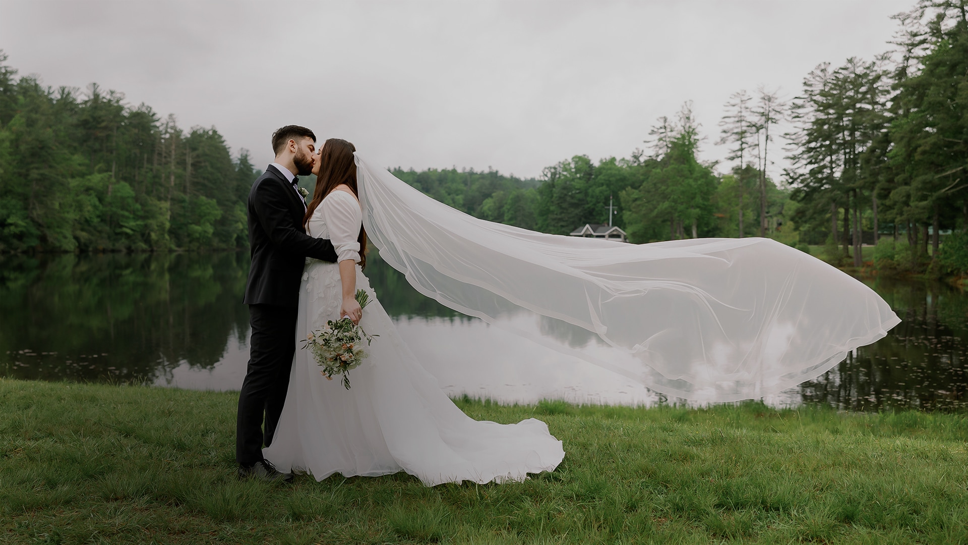 a man and woman kissing in front of a lake