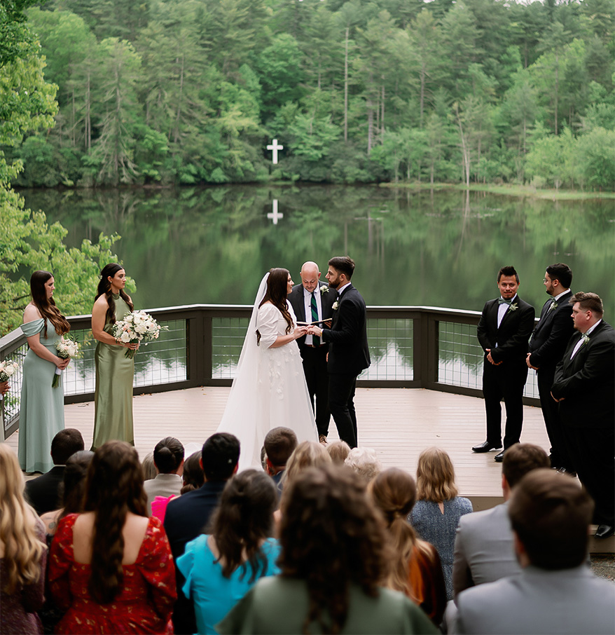 a couple in wedding attire on a deck with a group of people watching