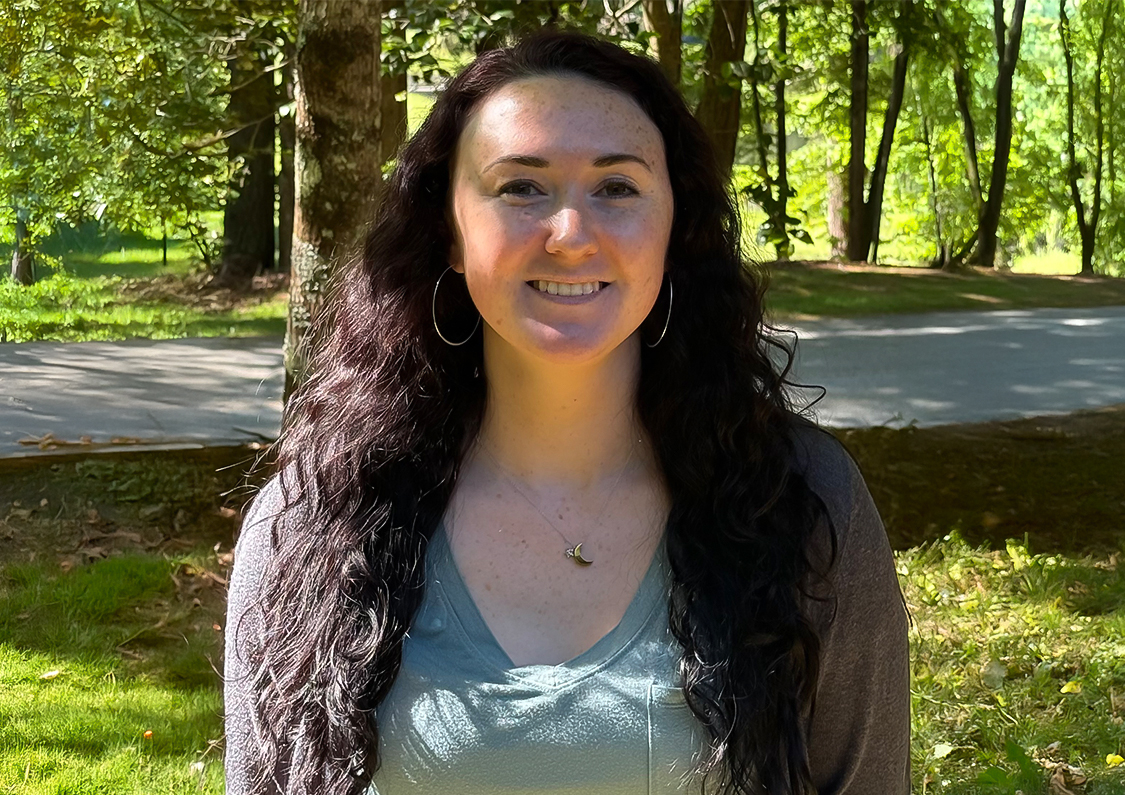 a woman with long hair smiling in a park