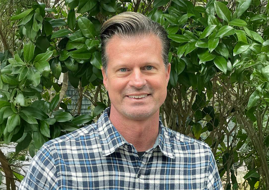 a man smiling in front of a tree
