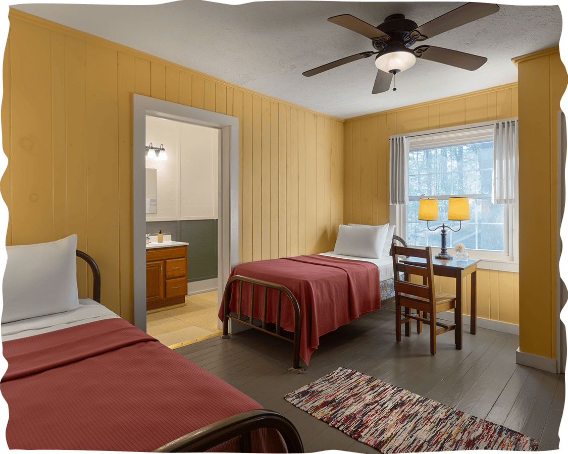 a bedroom with two beds and a table and a fan
