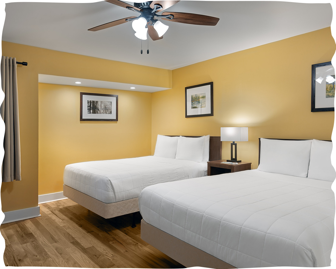 a room with two beds and a ceiling fan