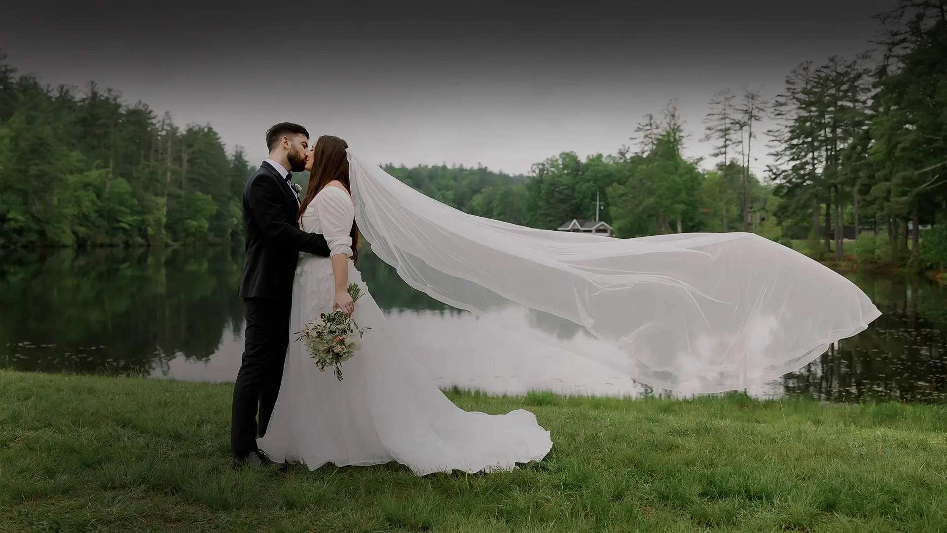 a man and woman kissing in front of a lake