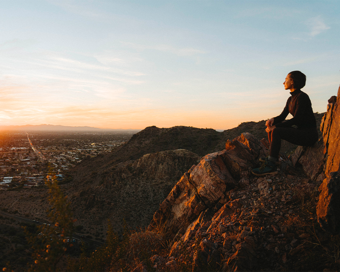 a person sitting on a rock looking at a city