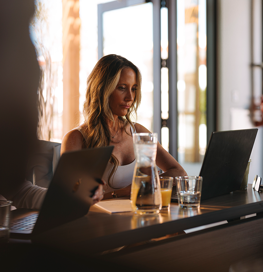 a woman sitting at a table with a laptop and glasses