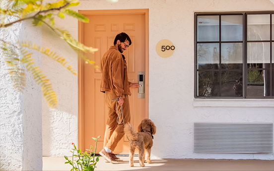 a man walking a dog on a leash outside a house