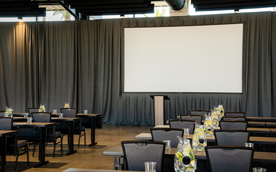 a room with tables and chairs and a projector screen