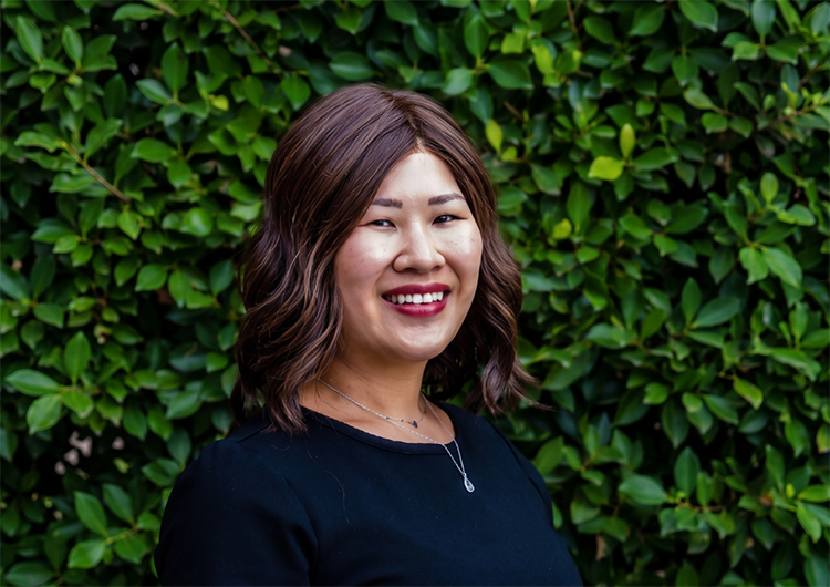 a woman smiling in front of a bush