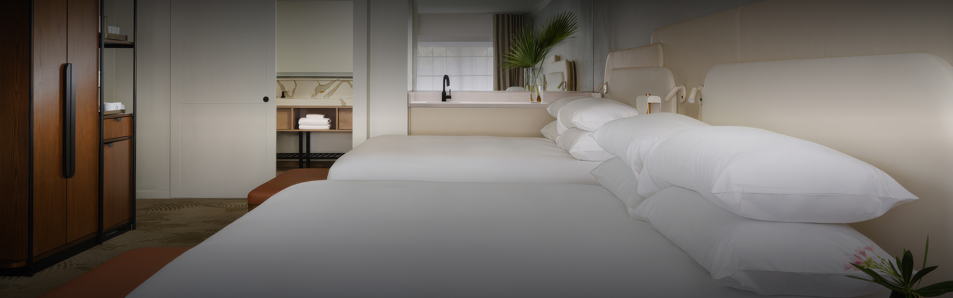 a bed with white sheets and a plant in a vase