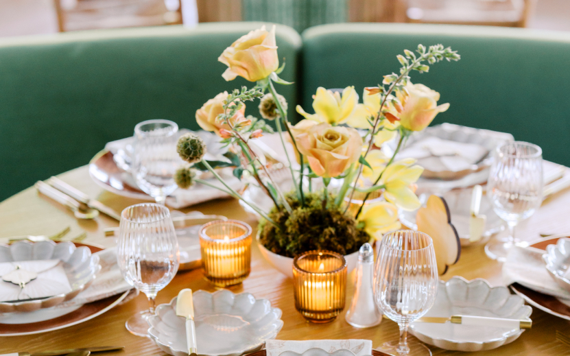 a table set with a vase of flowers and candles