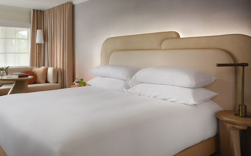a bed with white sheets and a tan headboard