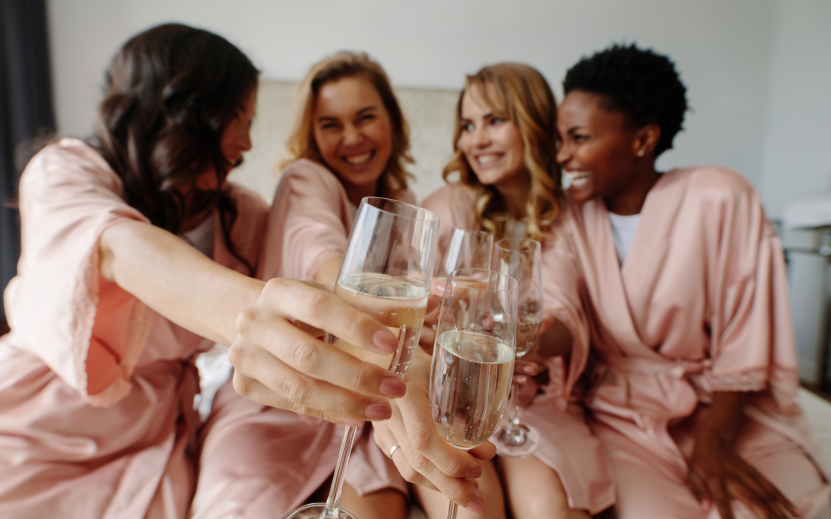a group of women in pink robes holding champagne glasses