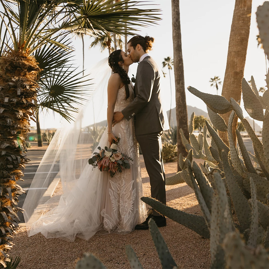 a man and woman kissing under a cactus