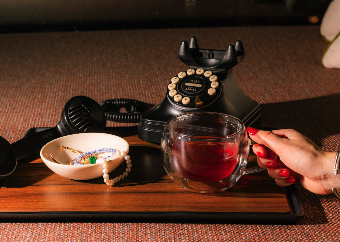 a hand holding a tea cup over a wooden surface