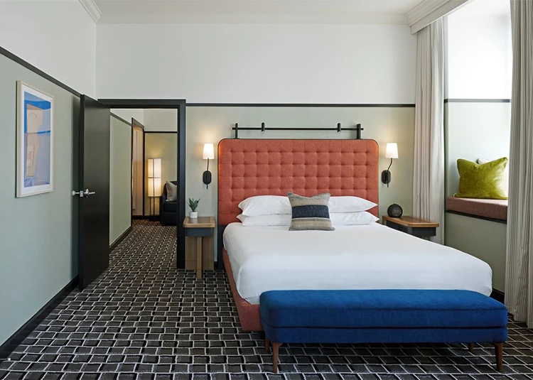 a bedroom with a bed and a blue ottoman
