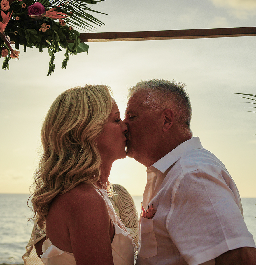a man and woman kissing under a floral arch