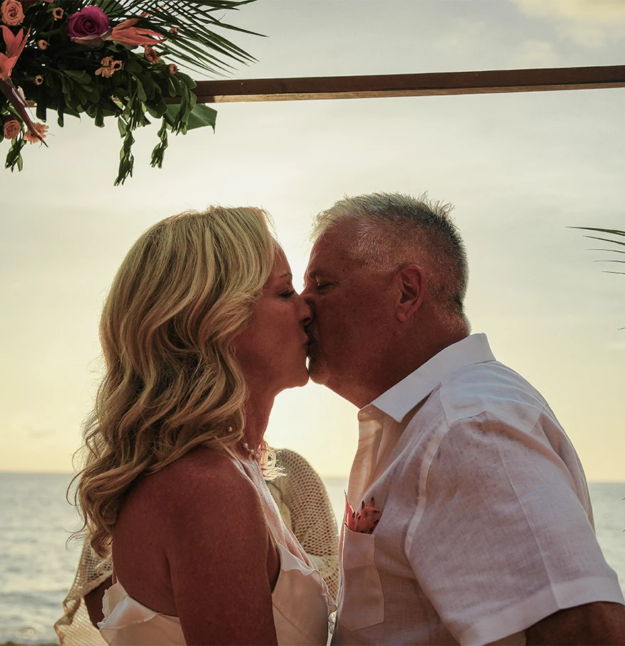 a man and woman kissing under a floral arch