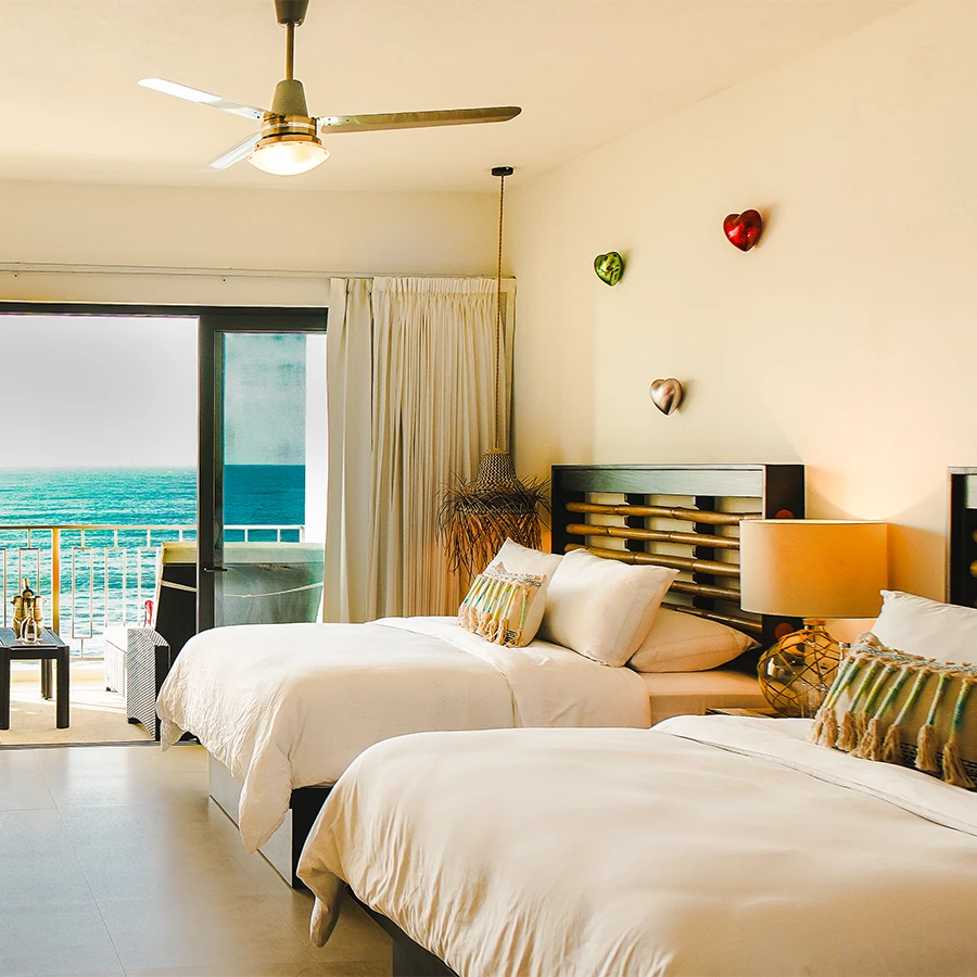 a room with two beds and a door to the ocean