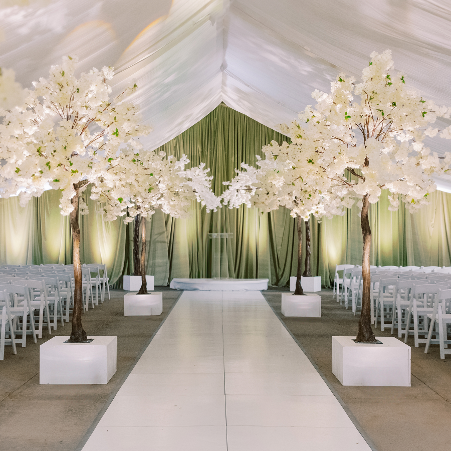 a white tent with white chairs and trees