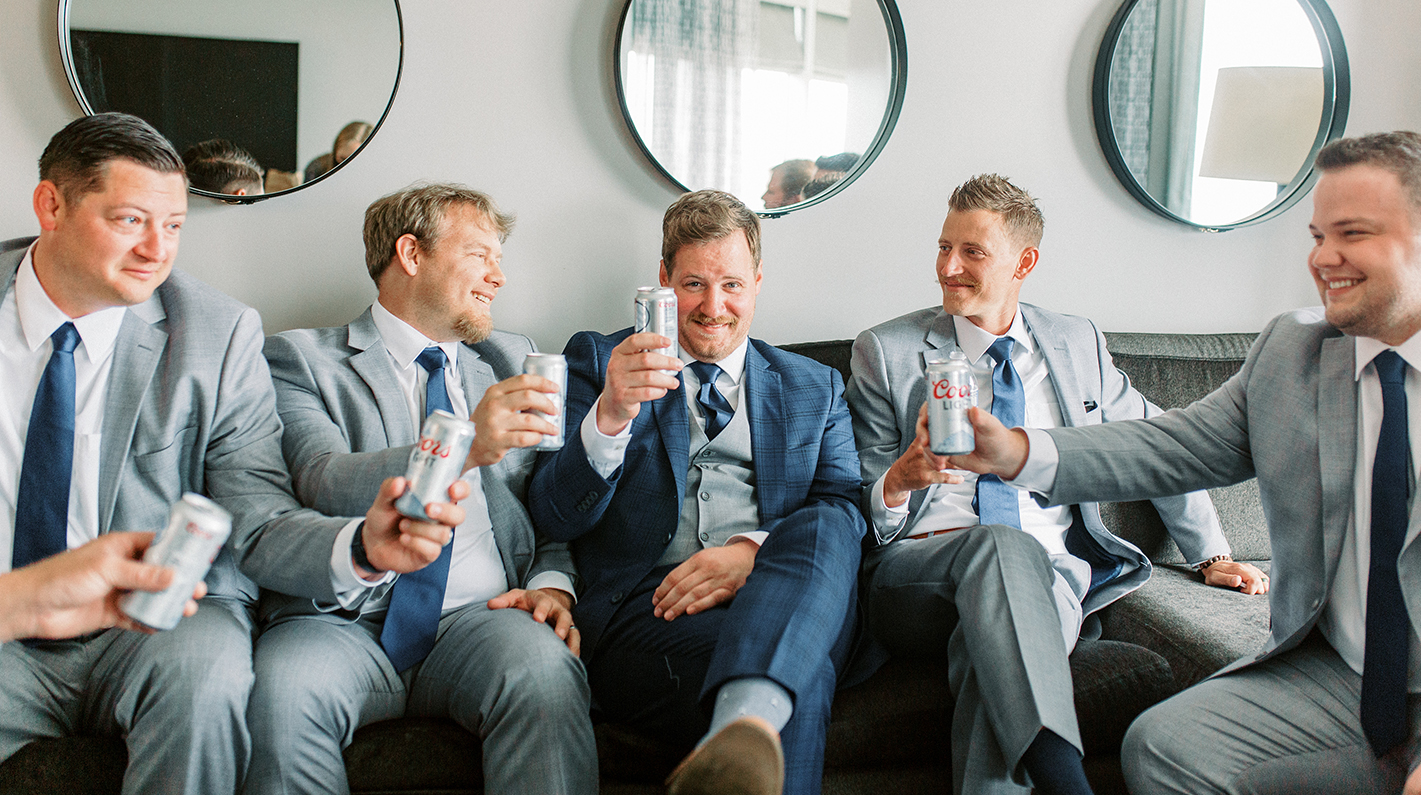 a group of men sitting on a couch holding cans of soda