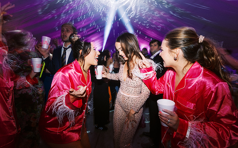 a group of women dancing in a room with people in the background