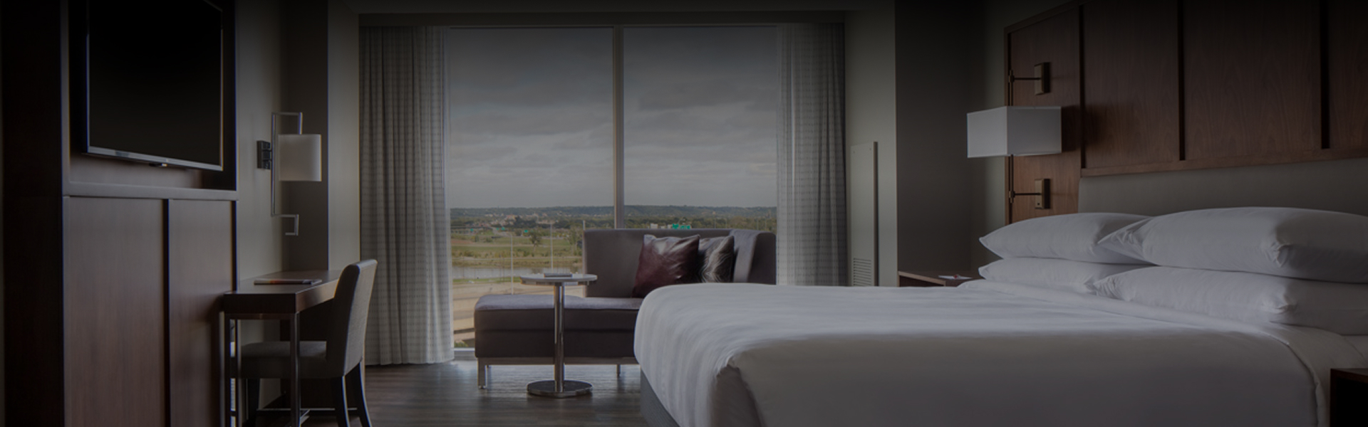 a bed and chair in a room with a view of a city