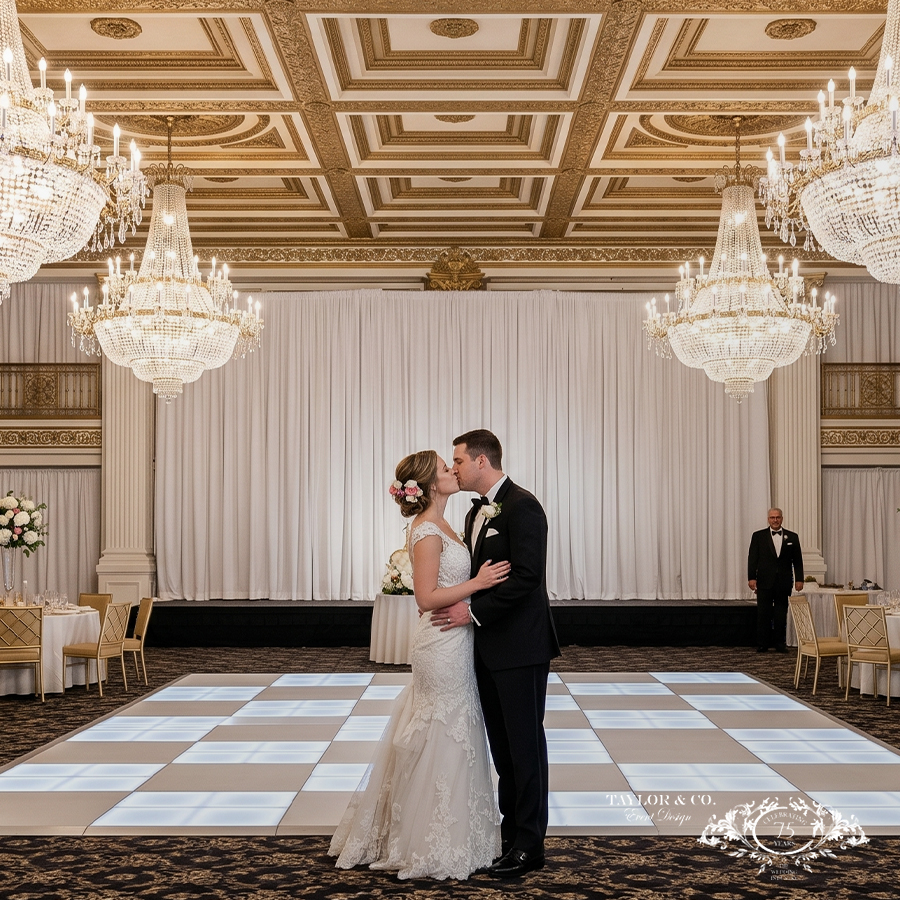 a man and woman kissing in a room with chandeliers