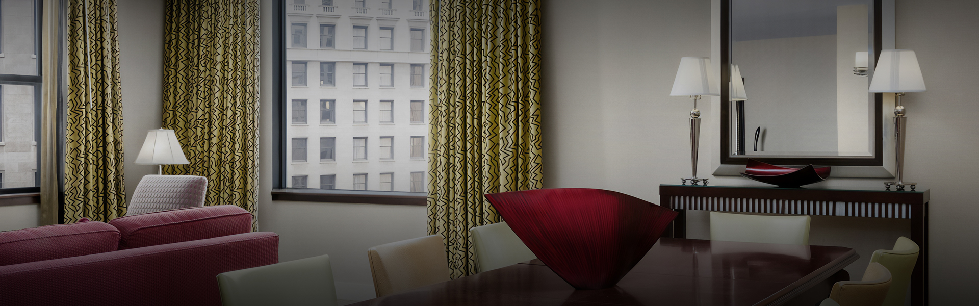 a red vase on a table in front of a window