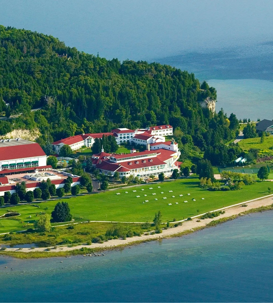 a large building with red roofs surrounded by a body of water