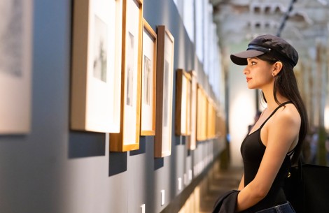 a woman looking at a wall with pictures on it
