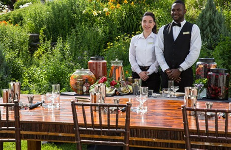 a man and woman standing next to a table with glasses and food