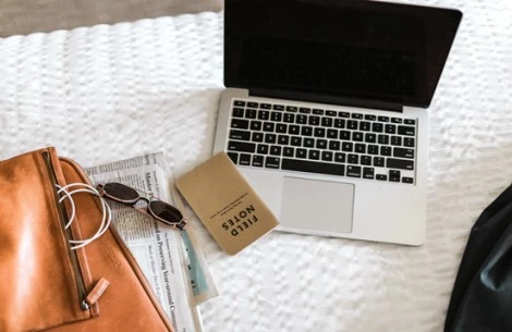 a laptop and sunglasses on a bed